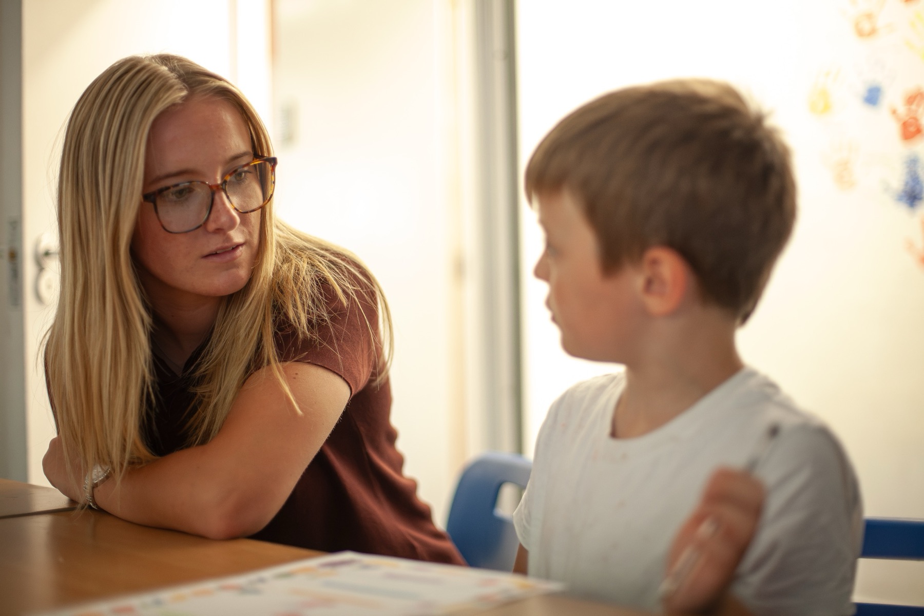 A member of staff working one to one with a young pupil at a classroom table